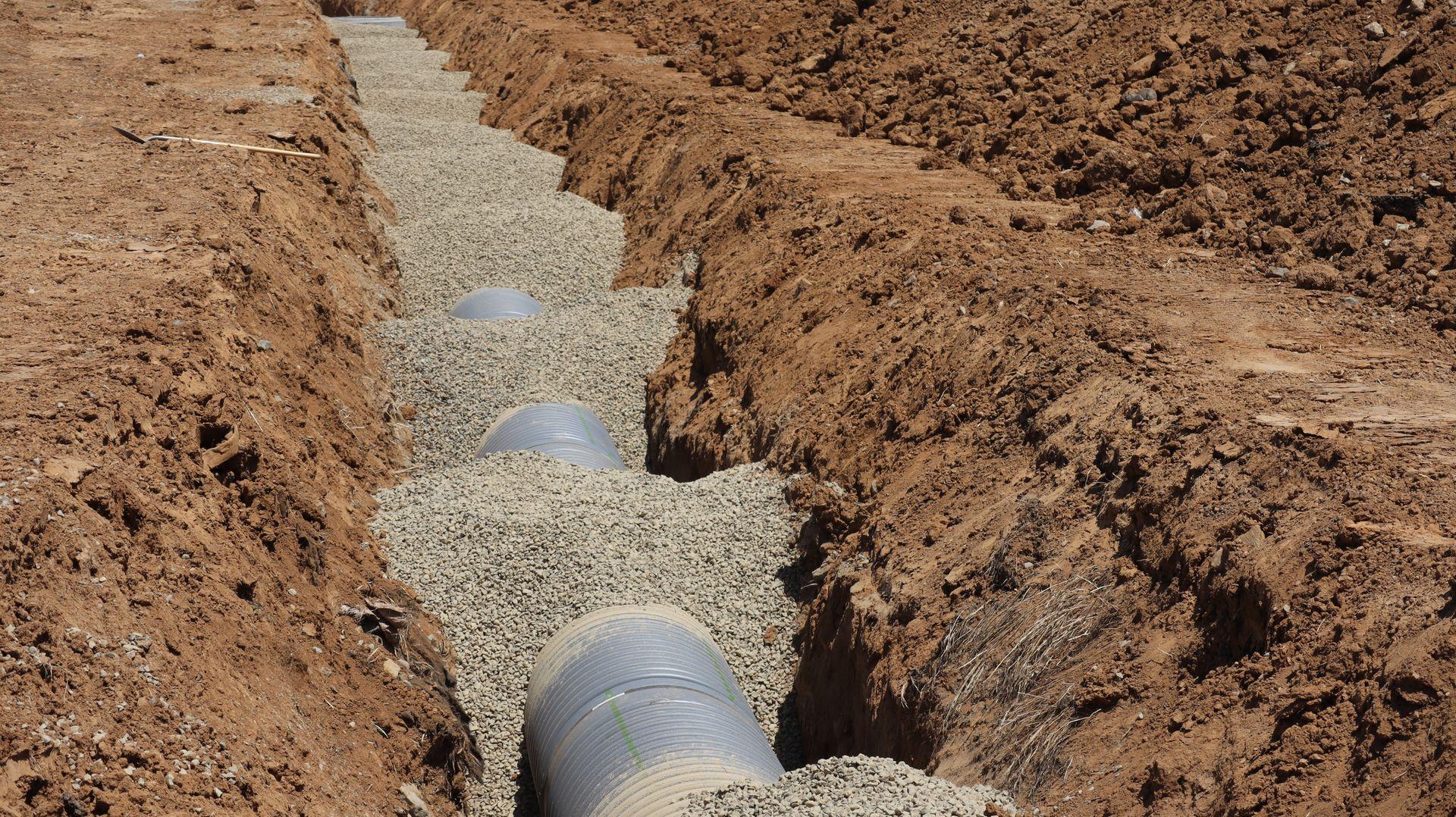Tubulação sendo instalada em vala aberta na terra