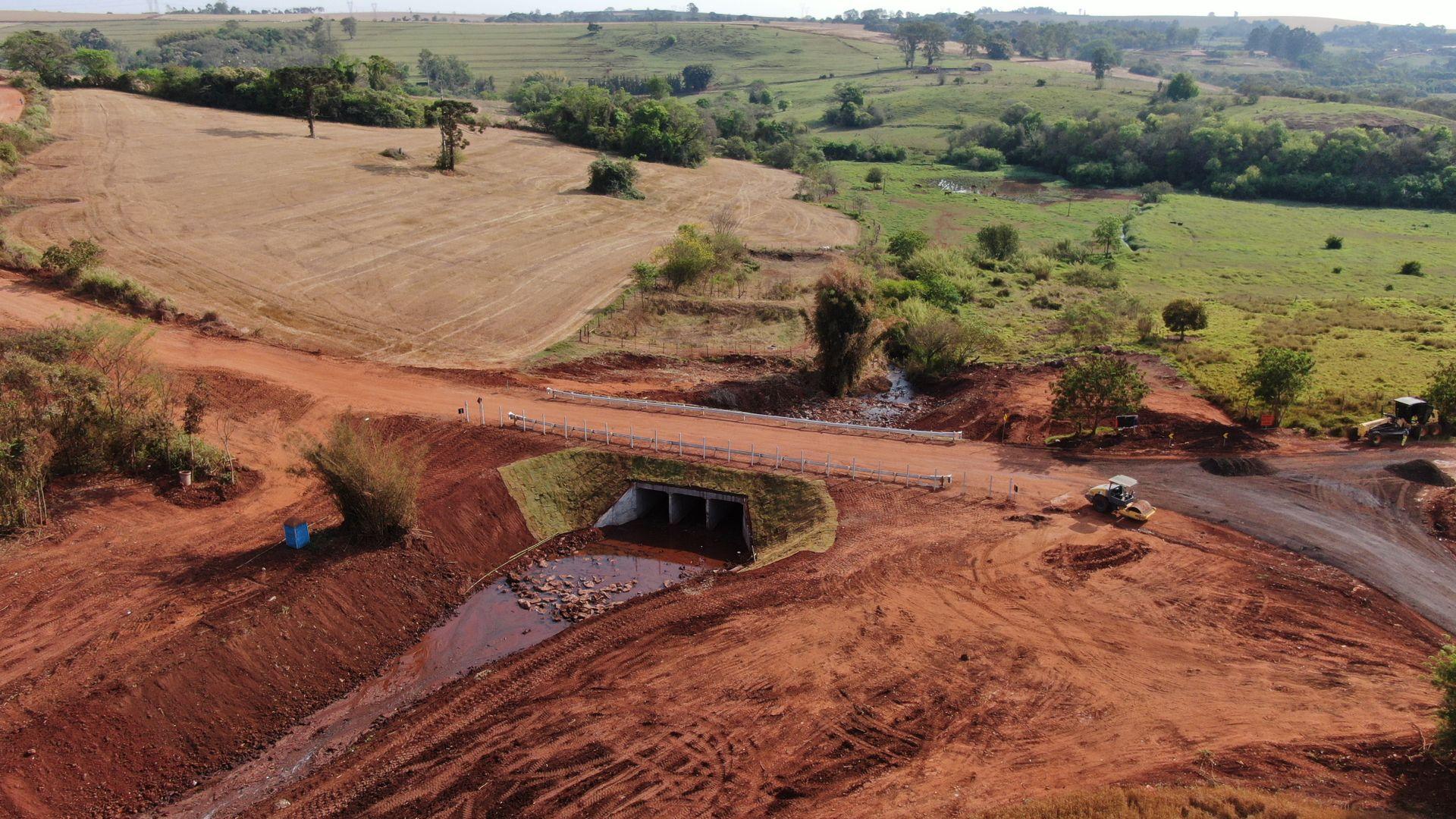 Terreno de terra vermelha com erosão e galeria de drenagem em área rural